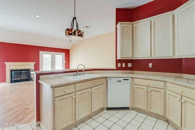 kitchen with tile countertops, white dishwasher, a sink, open floor plan, and pendant lighting