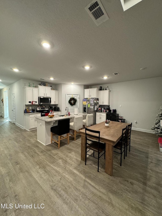 dining space featuring sink, wood-type flooring, and a textured ceiling