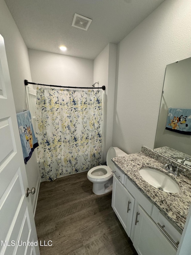 full bathroom with vanity, hardwood / wood-style flooring, toilet, and shower / bath combo with shower curtain