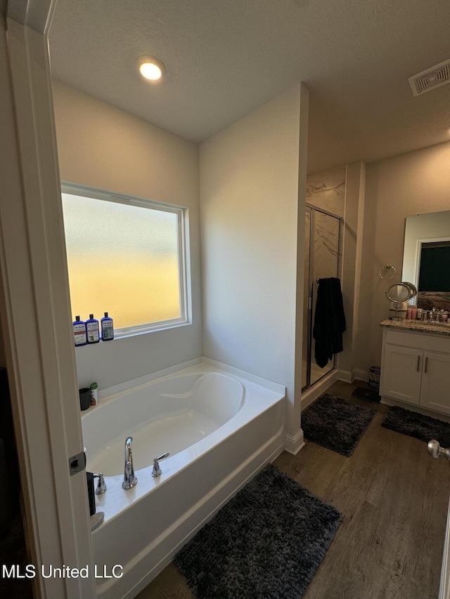 bathroom with a textured ceiling, vanity, hardwood / wood-style flooring, and separate shower and tub