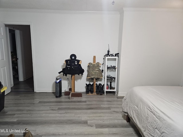bedroom featuring baseboards, wood finished floors, and ornamental molding