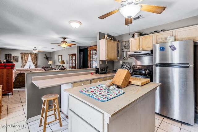 kitchen featuring stainless steel refrigerator, black electric range, light tile patterned flooring, a kitchen bar, and a kitchen island