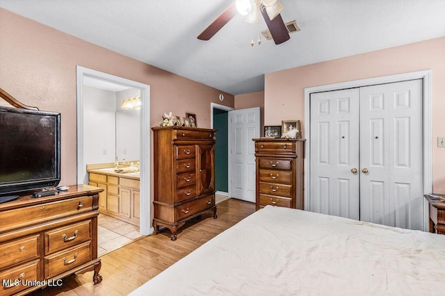 bedroom with ensuite bath, ceiling fan, light hardwood / wood-style floors, and a closet