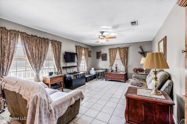 living room featuring ceiling fan, light tile patterned flooring, and a textured ceiling