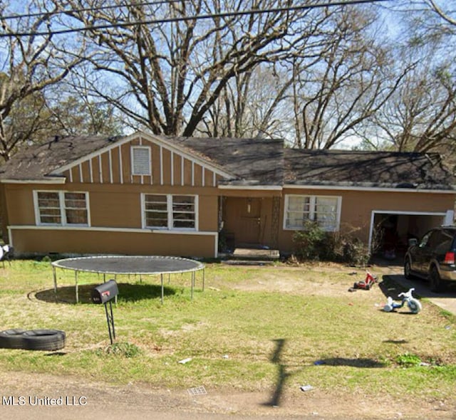 view of front of home featuring a front yard, a trampoline, and a garage