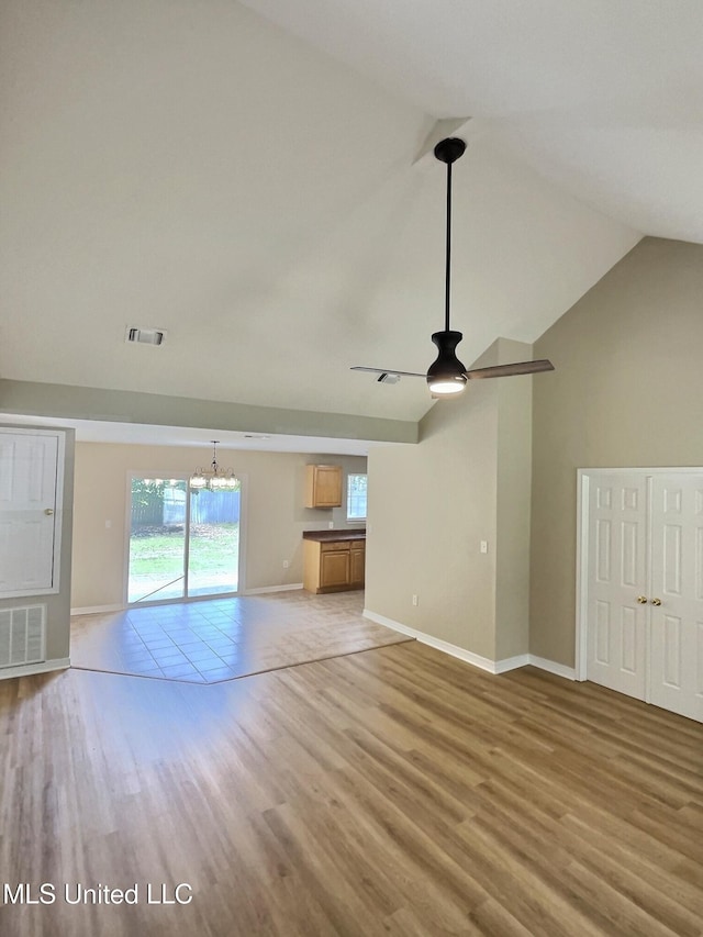 1204 Dorothy St, Ocean Springs, MS 39564 - unfurnished living room with light wood-style floors, vaulted ceiling, a ceiling fan, a chandelier, and plenty of natural light