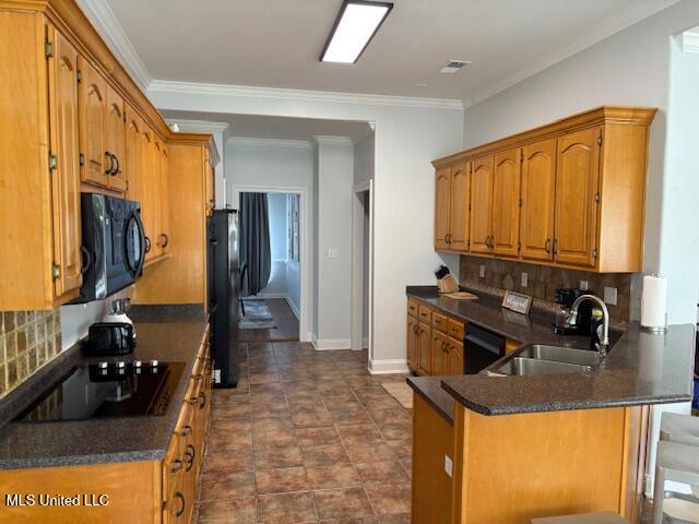220 Forked Creek Pkwy, Hernando, MS 38632 - kitchen featuring black appliances, a peninsula, dark countertops, brown cabinets, and crown molding