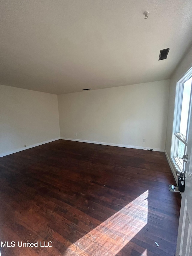 spare room with wood finished floors and baseboards