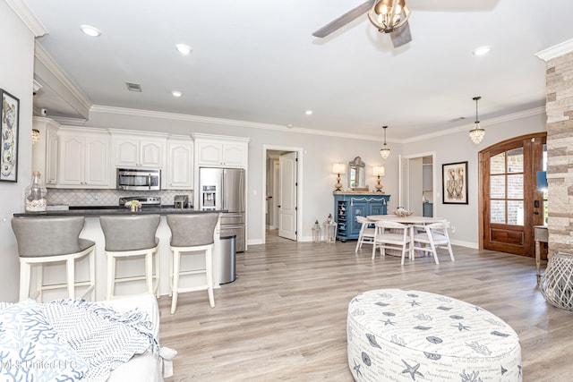 living room with ornamental molding, light hardwood / wood-style floors, and ceiling fan