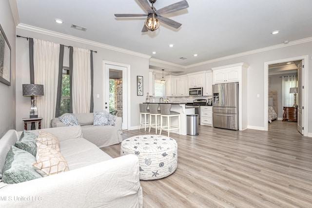 living room featuring light hardwood / wood-style floors, ornamental molding, and ceiling fan