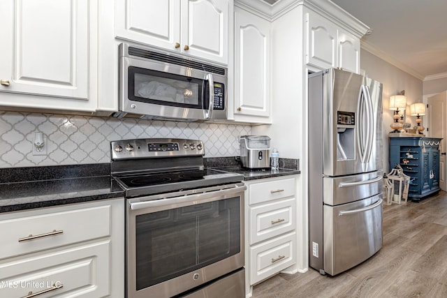 kitchen featuring appliances with stainless steel finishes, ornamental molding, white cabinetry, decorative backsplash, and light hardwood / wood-style flooring