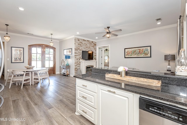 kitchen featuring stainless steel dishwasher, a fireplace, decorative light fixtures, and light hardwood / wood-style floors