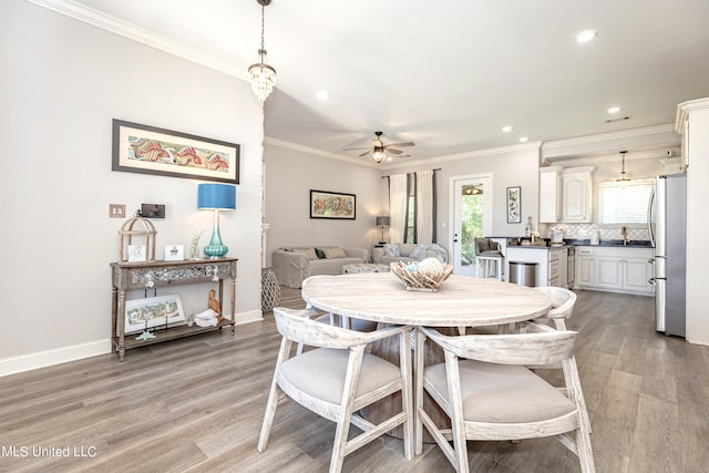 dining area with ceiling fan, crown molding, and wood-type flooring