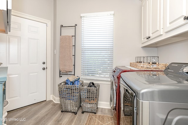 clothes washing area featuring light hardwood / wood-style flooring, washing machine and clothes dryer, a healthy amount of sunlight, and cabinets