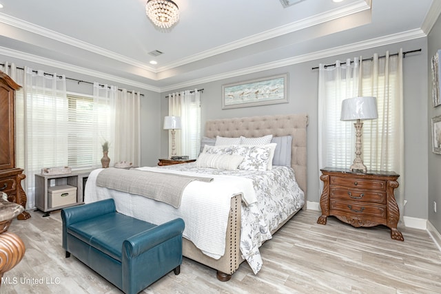 bedroom featuring crown molding, wood-type flooring, and a tray ceiling