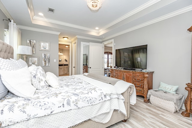 bedroom with light hardwood / wood-style flooring, crown molding, ensuite bathroom, and a tray ceiling