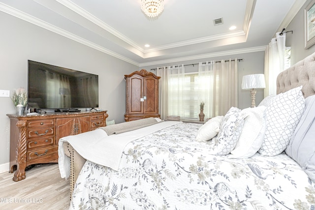 bedroom with light hardwood / wood-style floors, crown molding, and a tray ceiling