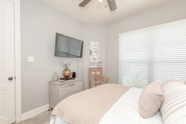 bedroom with ceiling fan, multiple windows, and light hardwood / wood-style floors