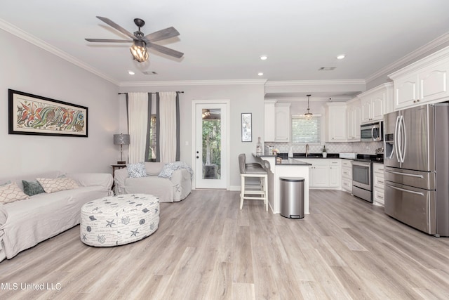 living room with ornamental molding, light wood-type flooring, and ceiling fan