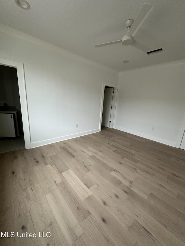 spare room featuring ceiling fan, ornamental molding, and light hardwood / wood-style flooring