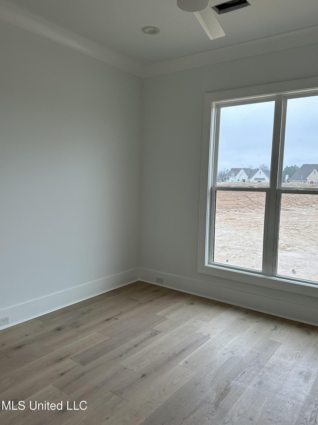 unfurnished room with ornamental molding, a wealth of natural light, and light wood-type flooring