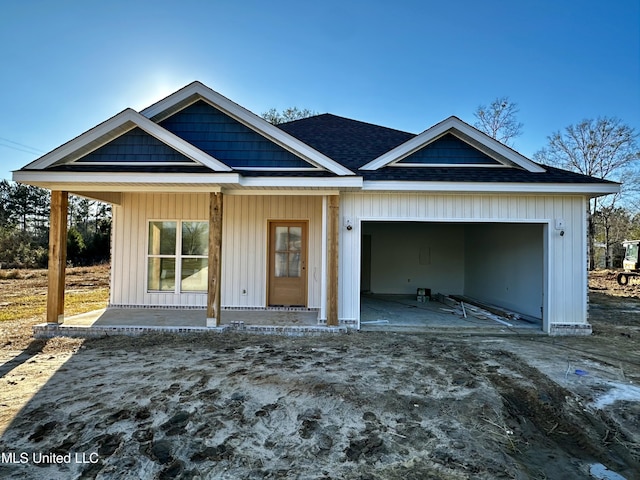 view of front of house with roof with shingles, a porch, board and batten siding, a garage, and driveway