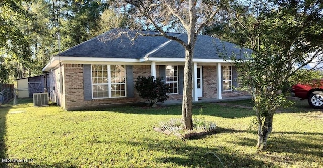 ranch-style home featuring cooling unit and a front lawn