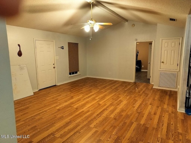 spare room featuring light wood-type flooring, a textured ceiling, vaulted ceiling with beams, and ceiling fan