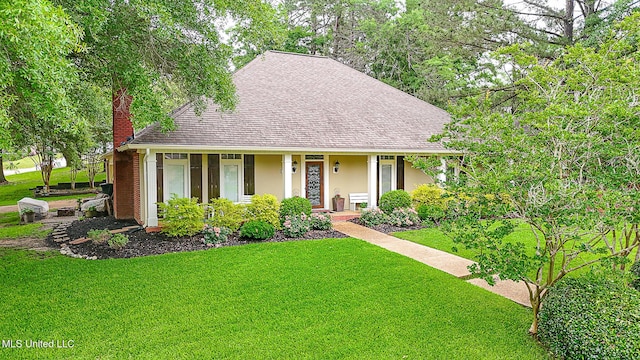 view of front of house featuring a chimney, stucco siding, a front yard, and a shingled roof