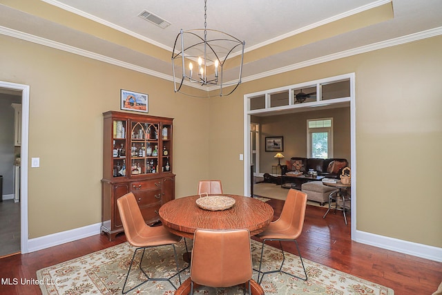 dining room featuring wood finished floors, a chandelier, crown molding, baseboards, and a tray ceiling