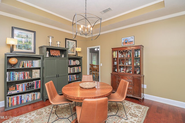 dining space featuring dark wood-type flooring, a chandelier, a tray ceiling, baseboards, and crown molding