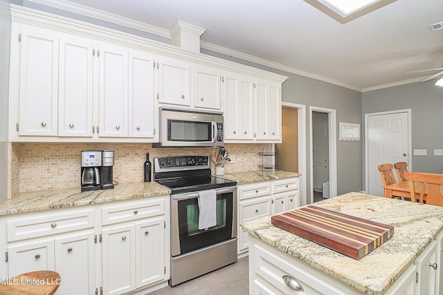 kitchen with stainless steel appliances, white cabinetry, decorative backsplash, ornamental molding, and light stone countertops
