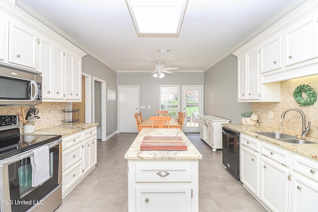kitchen featuring appliances with stainless steel finishes, a sink, decorative backsplash, light tile patterned floors, and a center island