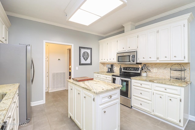 kitchen featuring appliances with stainless steel finishes, a kitchen island, crown molding, backsplash, and white cabinets
