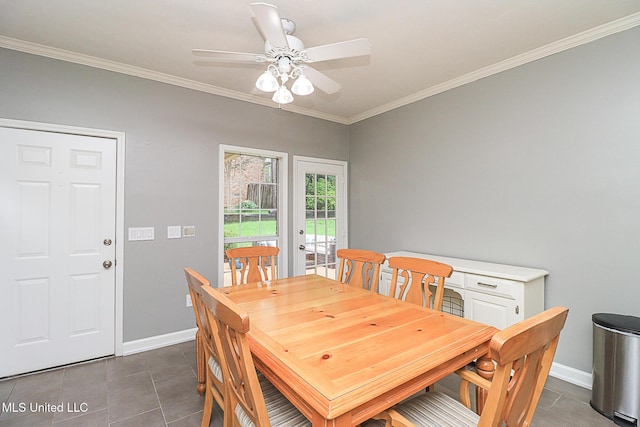 dining space with a ceiling fan, ornamental molding, baseboards, and dark tile patterned floors