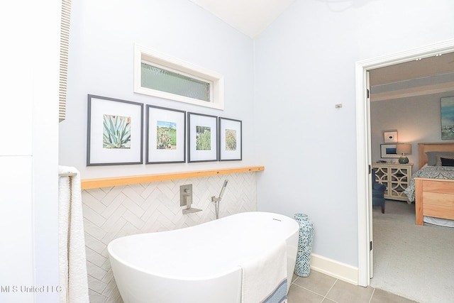 bathroom featuring tile patterned floors, a freestanding bath, connected bathroom, vaulted ceiling, and baseboards