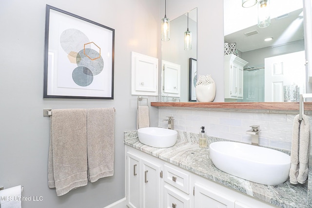 bathroom with decorative backsplash, double vanity, and a shower