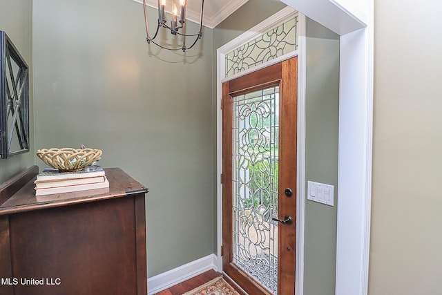 entrance foyer with a chandelier, ornamental molding, baseboards, and wood finished floors