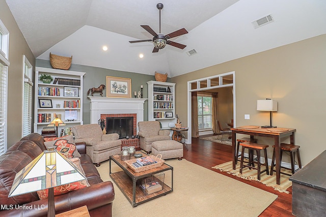 living area featuring wood finished floors, ceiling fan, lofted ceiling, a fireplace, and recessed lighting