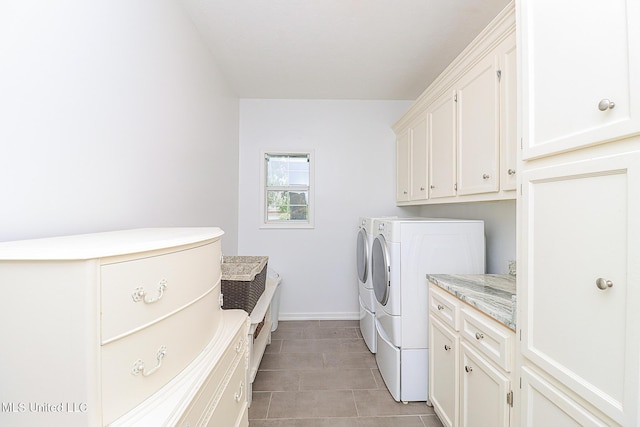 clothes washing area featuring washer and dryer, cabinet space, baseboards, and light tile patterned floors