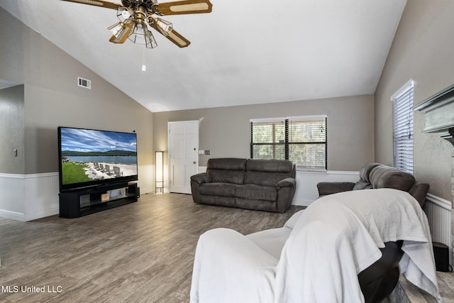 living room with high vaulted ceiling, a wainscoted wall, a ceiling fan, wood finished floors, and visible vents