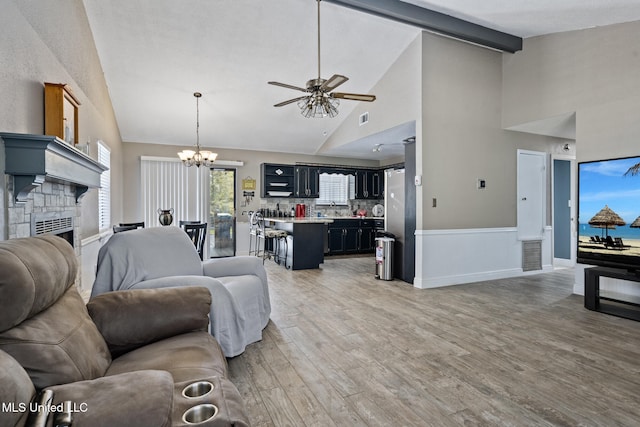 living area with beam ceiling, light wood-style floors, high vaulted ceiling, ceiling fan with notable chandelier, and visible vents