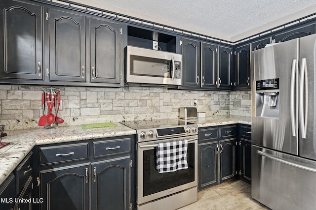 kitchen featuring backsplash, a textured ceiling, appliances with stainless steel finishes, and light wood-style floors
