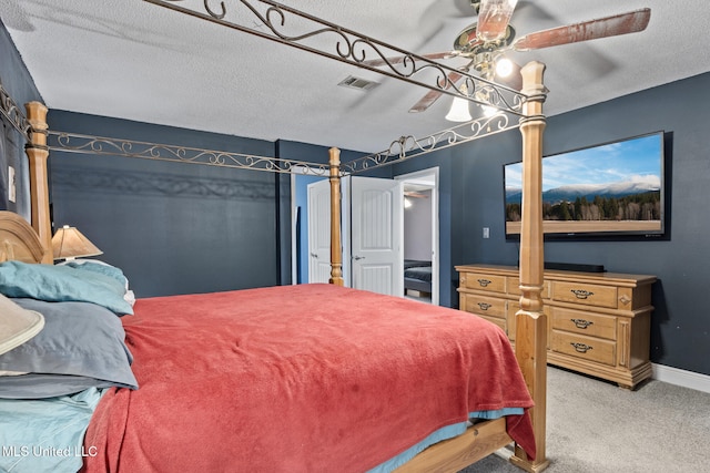 carpeted bedroom with a textured ceiling, baseboards, visible vents, and a ceiling fan
