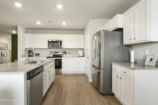 kitchen featuring white cabinets, appliances with stainless steel finishes, light wood-type flooring, and sink