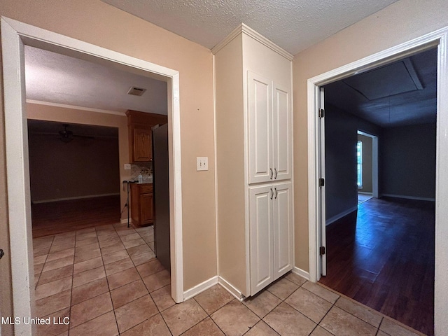 hall with crown molding, light hardwood / wood-style flooring, and a textured ceiling