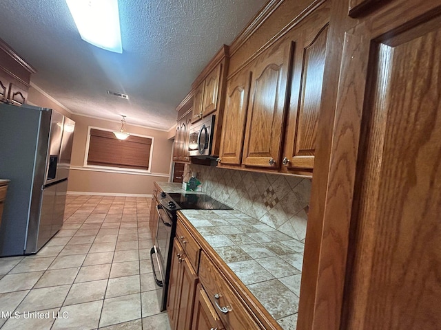 kitchen featuring light tile patterned floors, tile countertops, appliances with stainless steel finishes, a textured ceiling, and backsplash