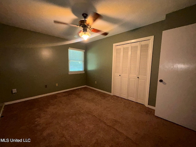 unfurnished bedroom with a closet, ceiling fan, and dark colored carpet