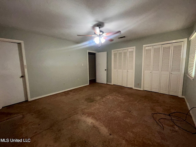 unfurnished bedroom with ceiling fan, multiple closets, and a textured ceiling