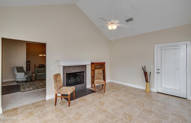 living room featuring a tiled fireplace, ceiling fan with notable chandelier, and high vaulted ceiling